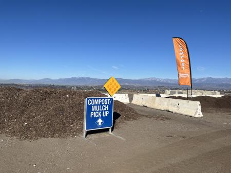 Piles of compost with a blue sign indicating this is the compost and mulch pick up area.